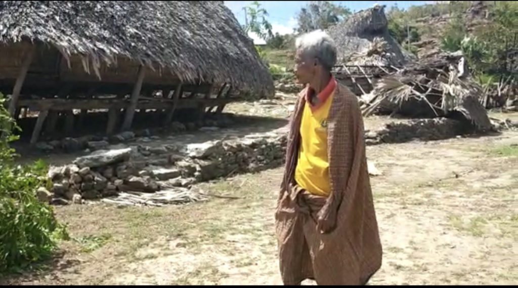 A man in fronVideo still of a man in front of destroyed house in Savu.t of destroyed house in Savu